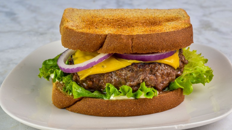 Cheeseburger on toasted bread with lettuce and onion