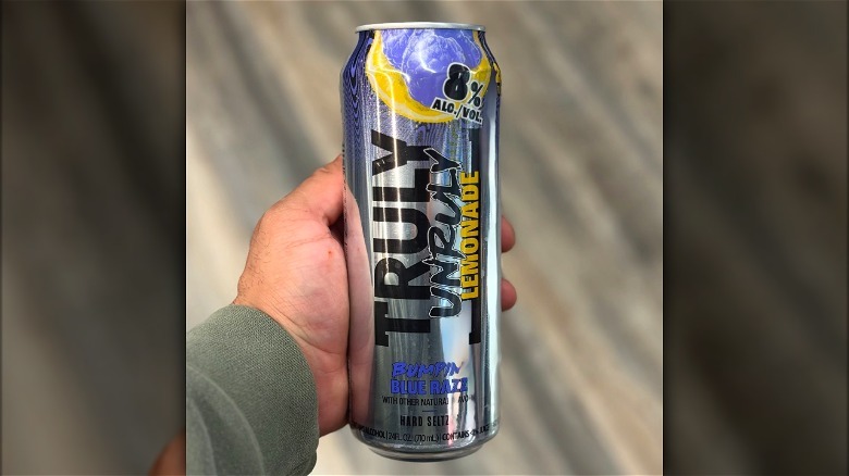 Hand holding can of Truly Unruly Bumpin' Blue Razz.