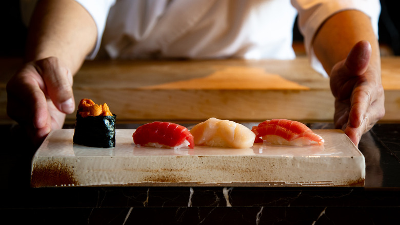 Person holding tray of sushi and sashimi
