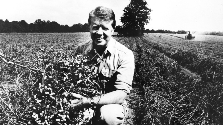 A black-and-white photo of Jimmy Carter smiling on his peanut farm