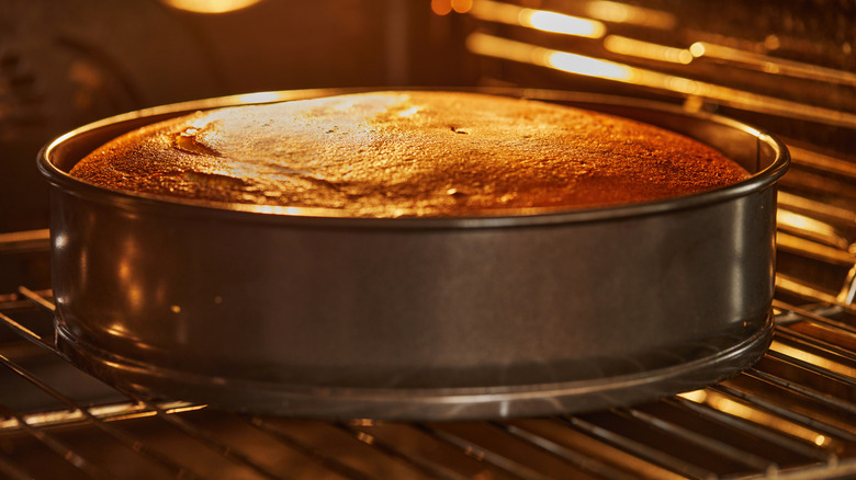 A golden cake bakes in a tin in the oven.