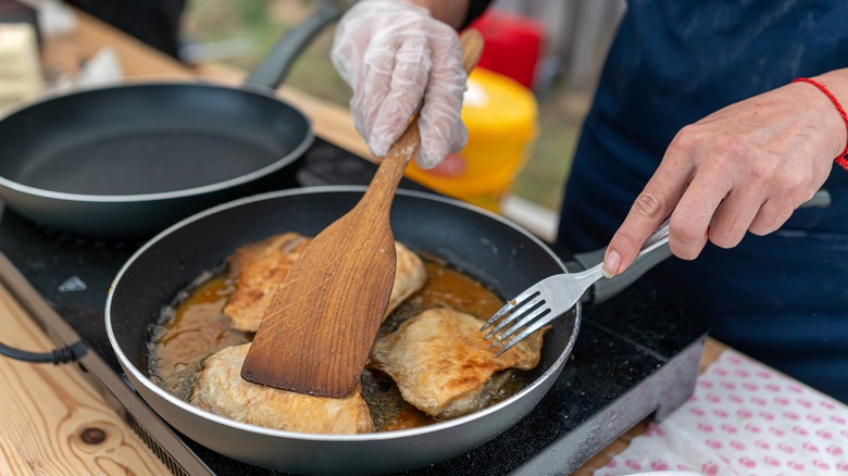 A cook sautes fish filets in a nonstick skillet
