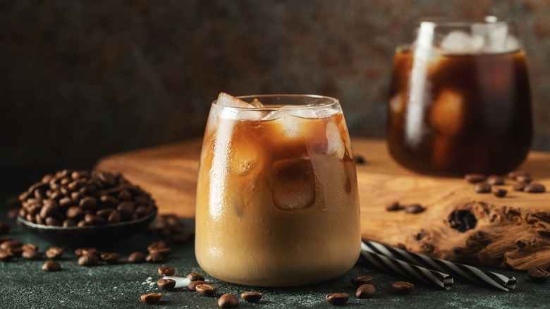 Glass of iced coffee with beans and another glass in the background
