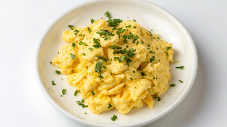 a plate of scrambled eggs garnished with green herbs