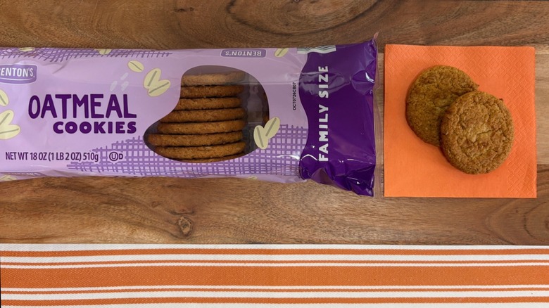 Benton's Oatmeal Cookies package next to two cookies on orange napkin