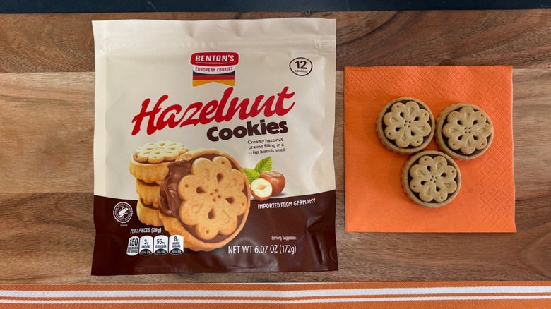 Benton's Hazelnut cookie package next to three cookies on an orange napkin
