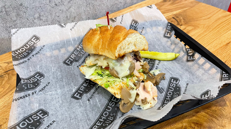 Engineer sub and dill pickle spear in a black basket on wooden table