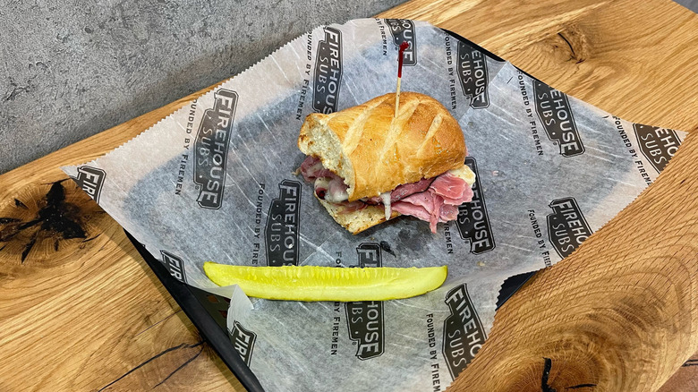 New York Steamer sub and dill pickle spear in a black basket on wooden table