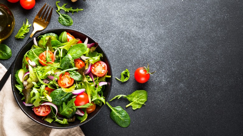 A bowl of salad with a fork on the side