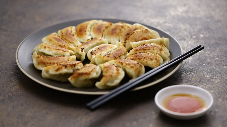 Potstickers plated with chopsticks and sauce