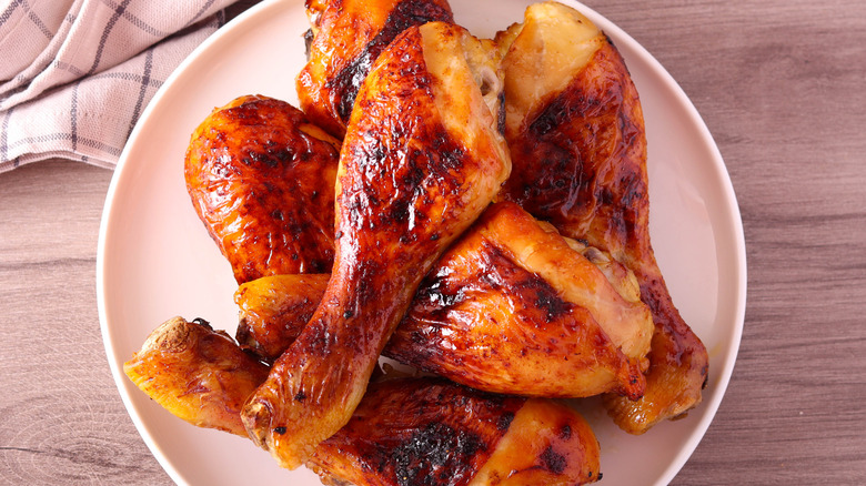 A bowl with roasted chicken drumsticks stacked up.