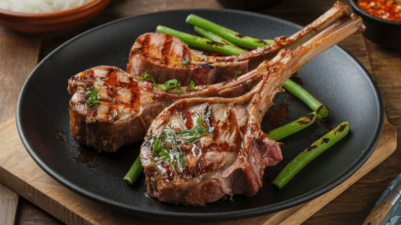 Mouthwatering charred lamb with fresh garnish on a black plate, sitting atop a wooden board