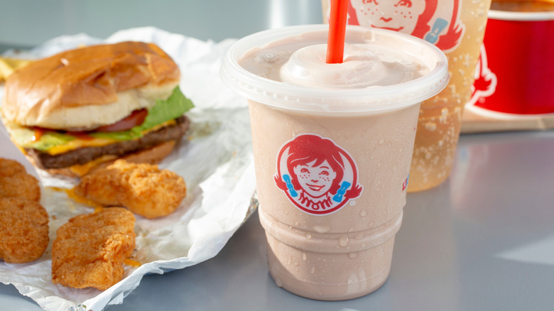Close up of a Wendy's Frosty with a cheeseburger and chicken nuggets in the background