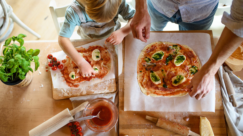 Child and parent making pizza