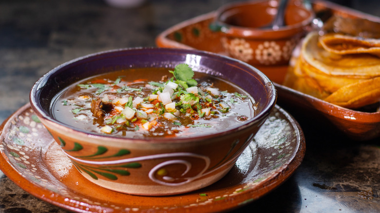 Mexican soup with chopped onions and cilantro with a side of tortillas