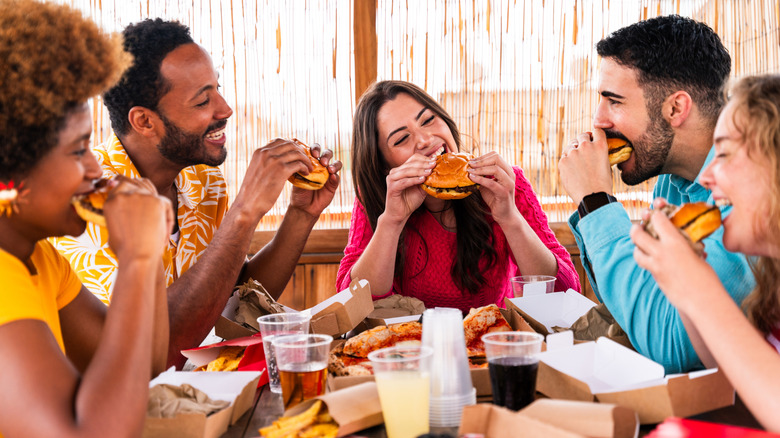 Group of people eating burgers at a fast food restaurant