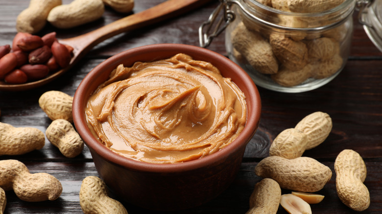 A bowl of peanut butter surrounded by peanuts