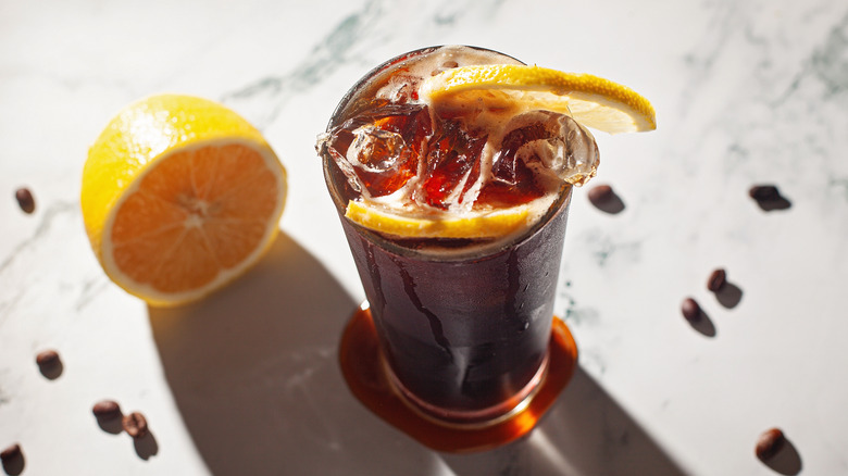 A refreshing glass of Mazagran coffee, topped with ice and two slices of lemon
