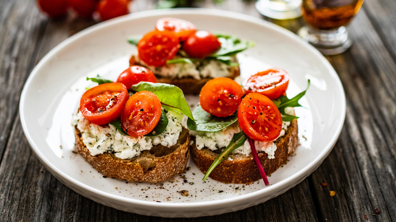 Cottage cheese with greens and tomatoes served on toast