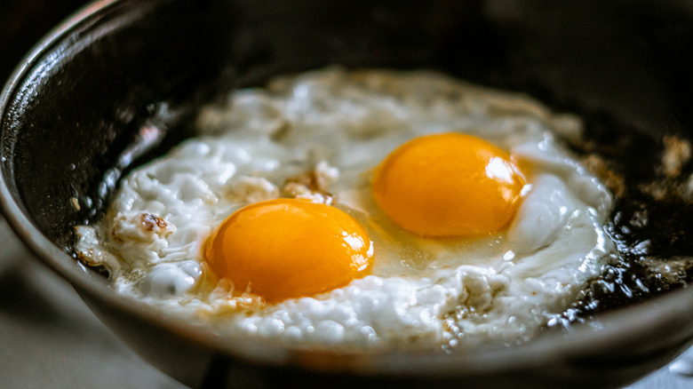 two eggs frying in a cast iron pan