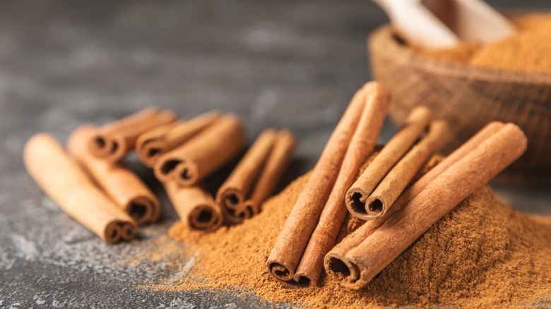 Cinnamon sticks over a pile of ground cinnamon.