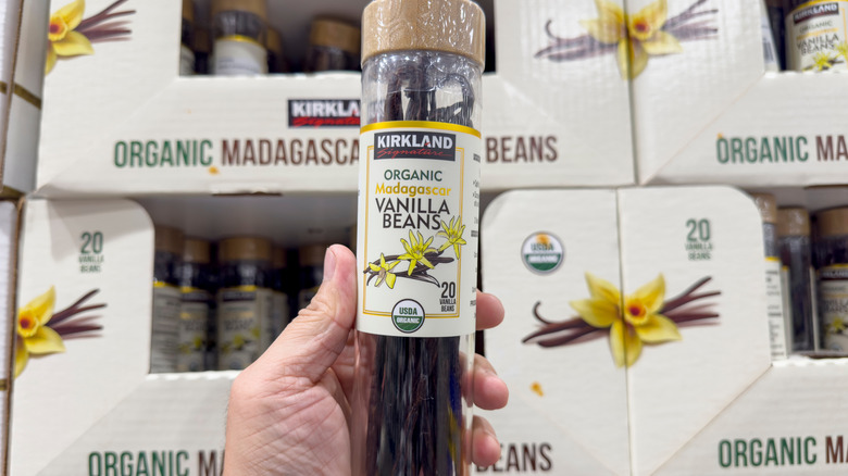 a hand holding a container of kirkland signature vanilla beans
