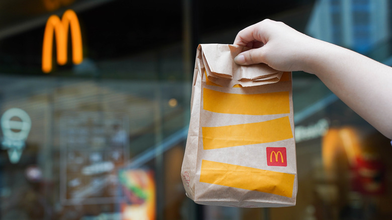 Person holding a McDonald's bag up in front of the restauarant