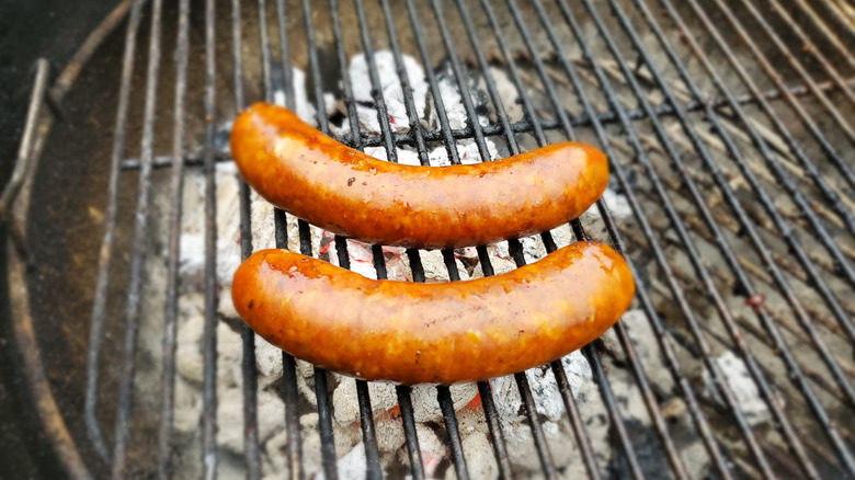 Two juicy sausages on a charcoal grill