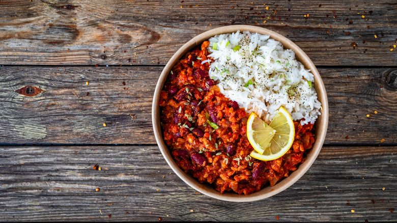 A bowl of chili and rice beautifully presented with slices of lemon