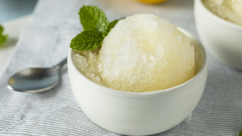 Corn granita in a bowl with a sprig of mint.
