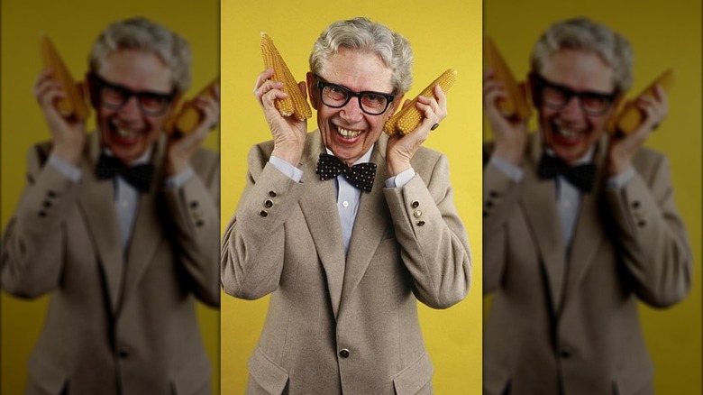 Orville Redenbacher holding corn cobs up to his face and smiling