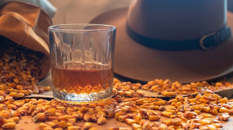 Glass of bourbon with sack of corn spilling around it