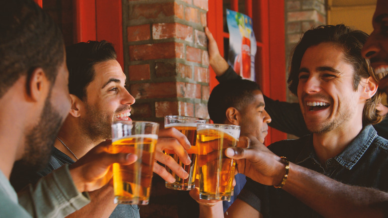 A group of people toast with beers.