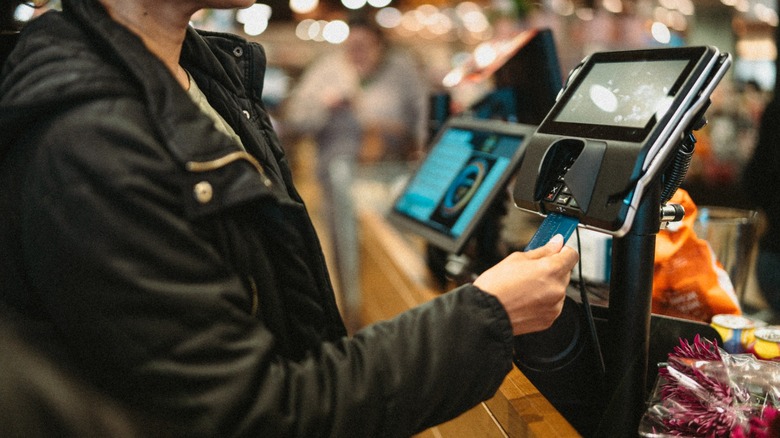 An empty shopping cart in front of a supermarket's refrigerated aisle.