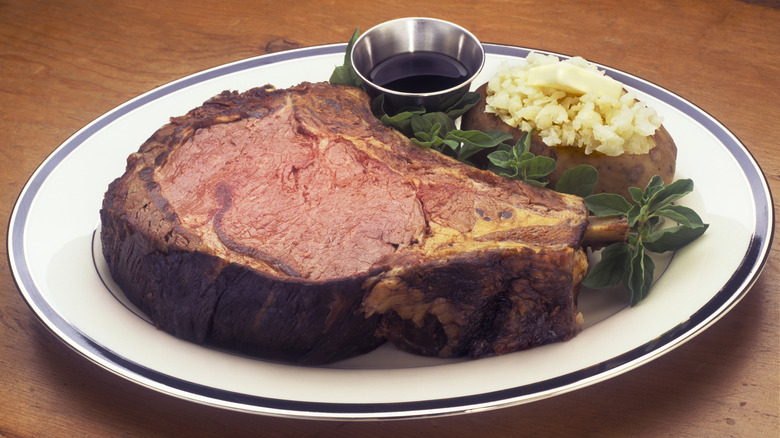 A plate of prime rib with a baked potato