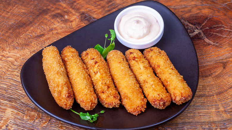 Fried cheese sticks on plate with white sauce