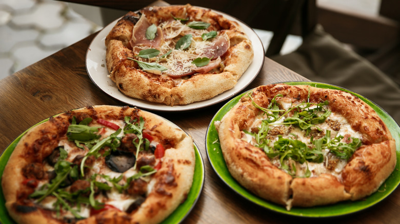 Personal size pizzas on green plates