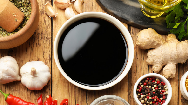 Soy sauce and other different ingredients for marinade on wooden table, flat lay.