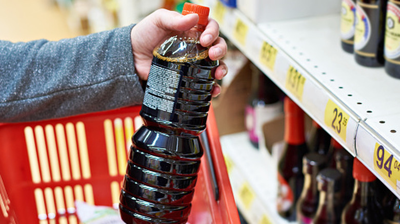 Soy sauce bottle in the hand of the buyer at the grocery store.