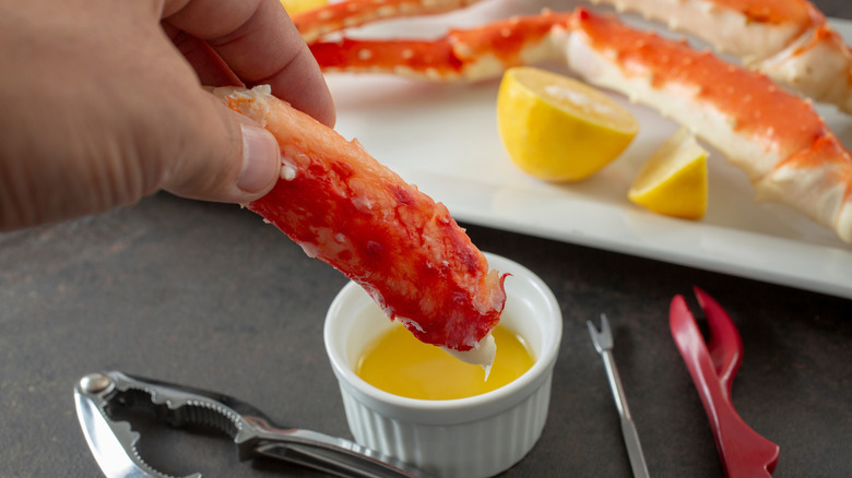 Hand dipping whole crab leg into butter sauce