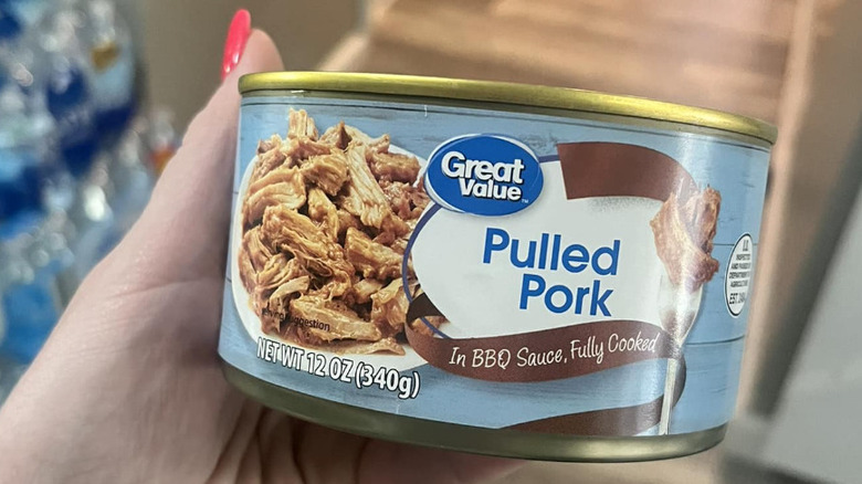 Hand holding pulled pork can