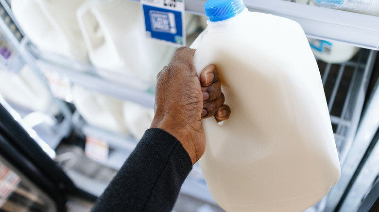 hand holding gallon of milk
