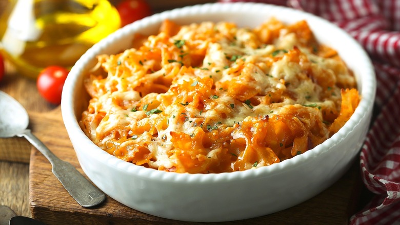 Baked noodles with tomato sauce and melted cheese in a white oval casserole dish