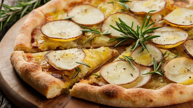 Italian potato pizza on top of wood pizza board.