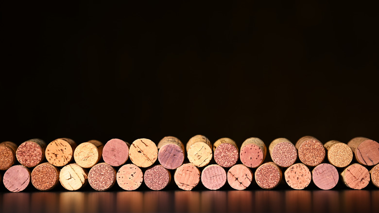 Border of assorted wine corks on a black background.