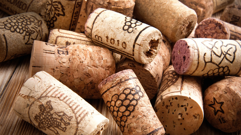 Assorted used wine corks on wood table.