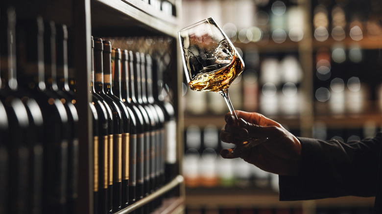 A sommelier swirling a glass of white wine.