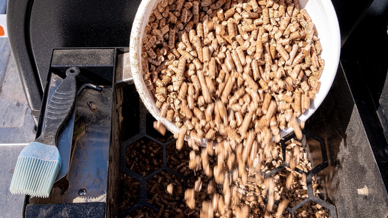 Wood pellets poured into smoker