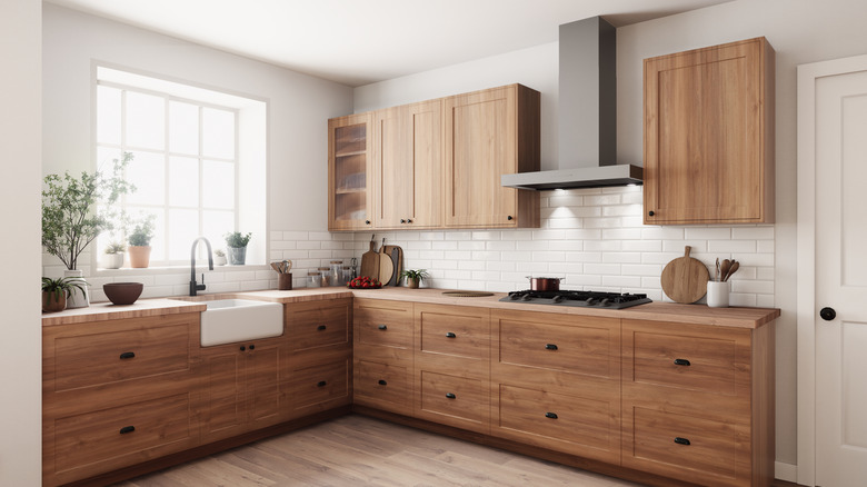 A home kitchen's wooden cabinets are cool-toned.