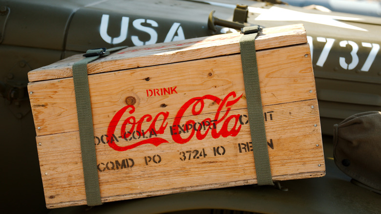 A wooden crate from Coca-Cola strapped to a military vehicle
